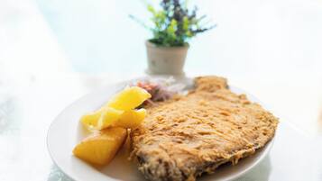 A plate with a fried fish, pineapple chunks, and a small salad.