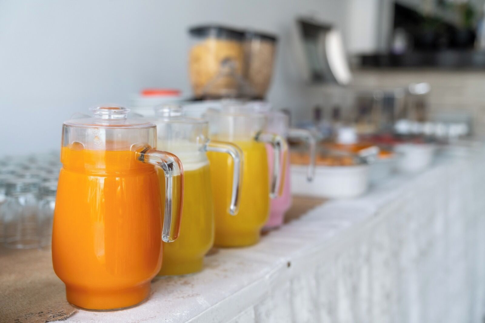 A breakfast buffet with various beverages in clear glass containers.