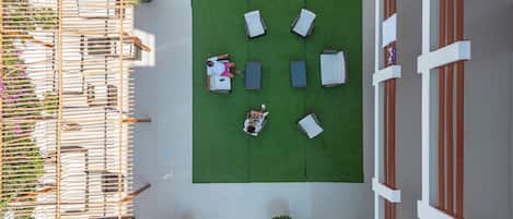 An aerial view of a rooftop garden with a seating area, a wooden pergola, and a staircase leading to an upper level.