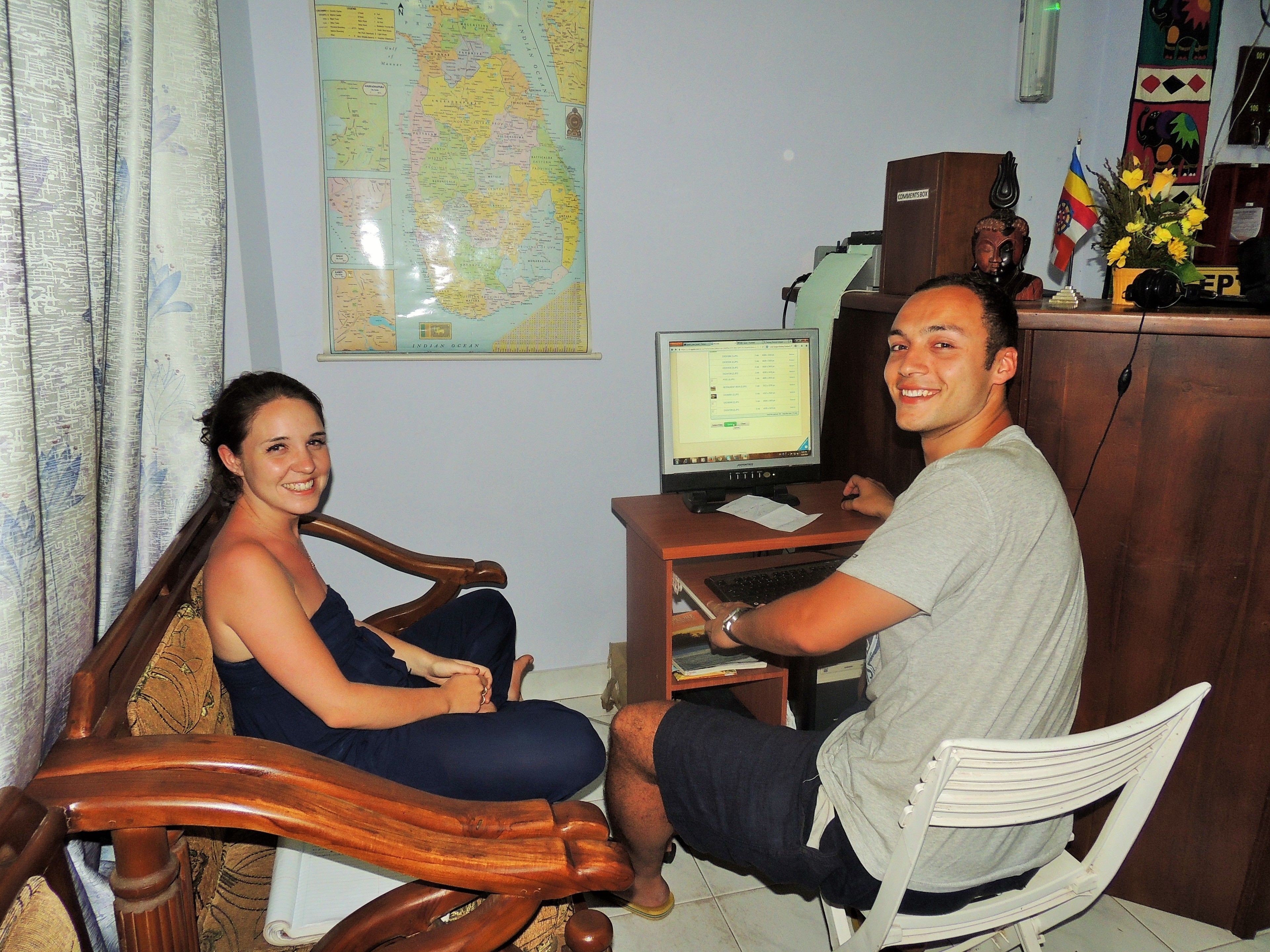 A room with a wooden desk, a computer, and a map on the wall.