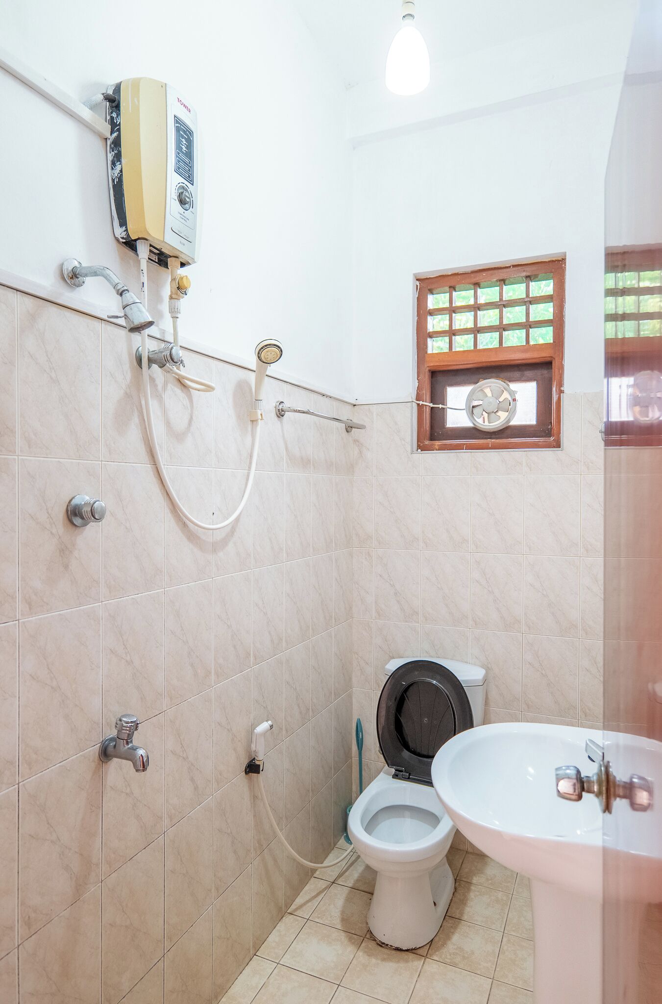 Une salle de bain équipée de toilettes, d’un lavabo, d’une douche et d’un chauffe-eau.