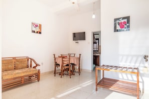 A living room with a sofa, dining table, chairs, a TV, and artwork on the walls. - Airport Green View Resort (Seeduwa - Katunayake)