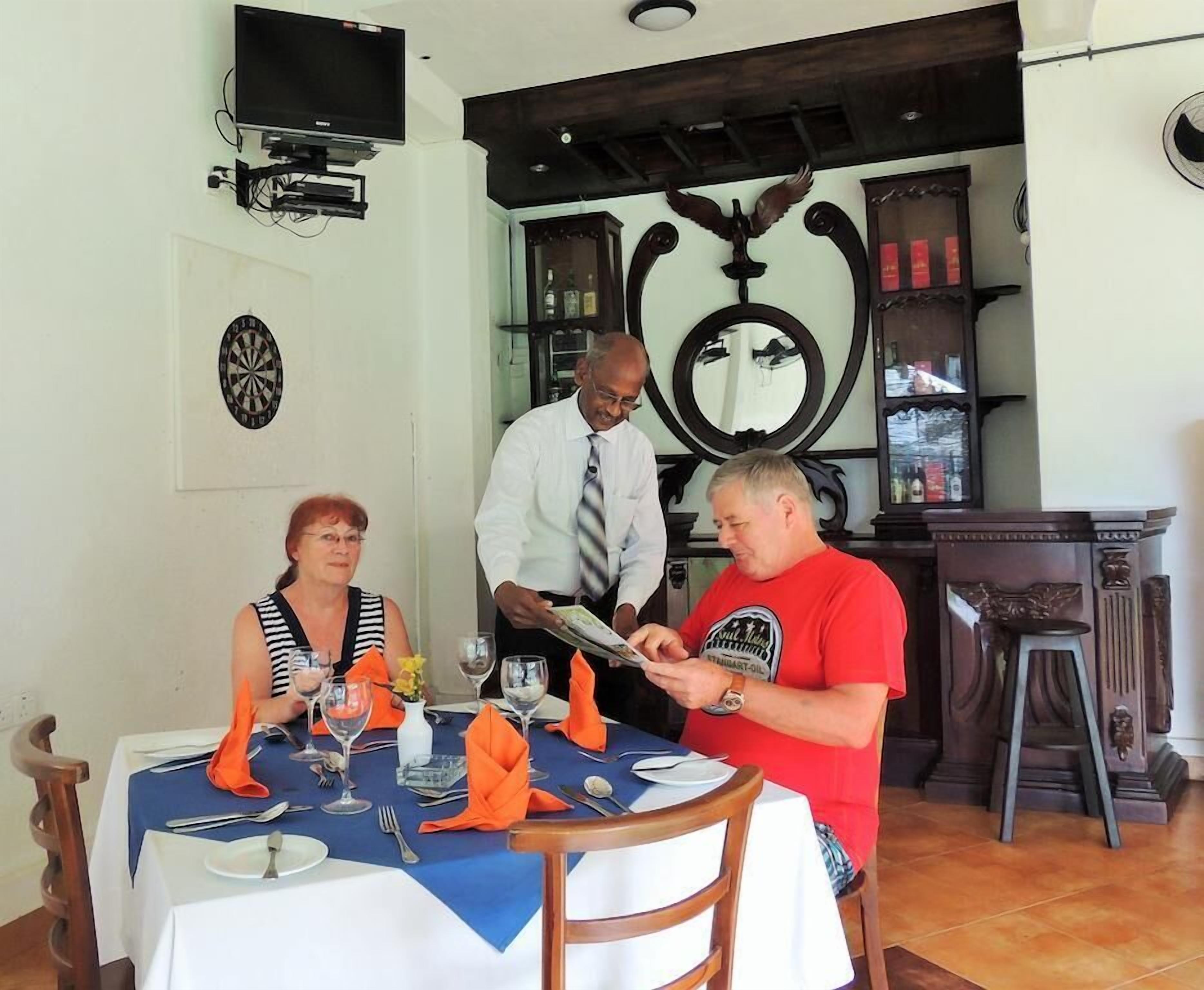 A dining area with a table set for three, a dartboard, and a television mounted on the wall.