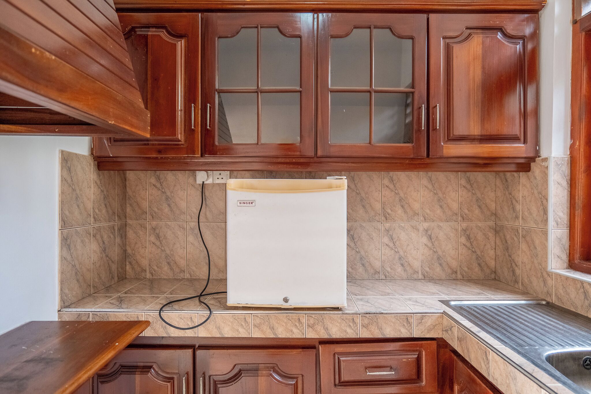 A kitchen with wooden cabinets, a marble backsplash, and a built-in refrigerator.