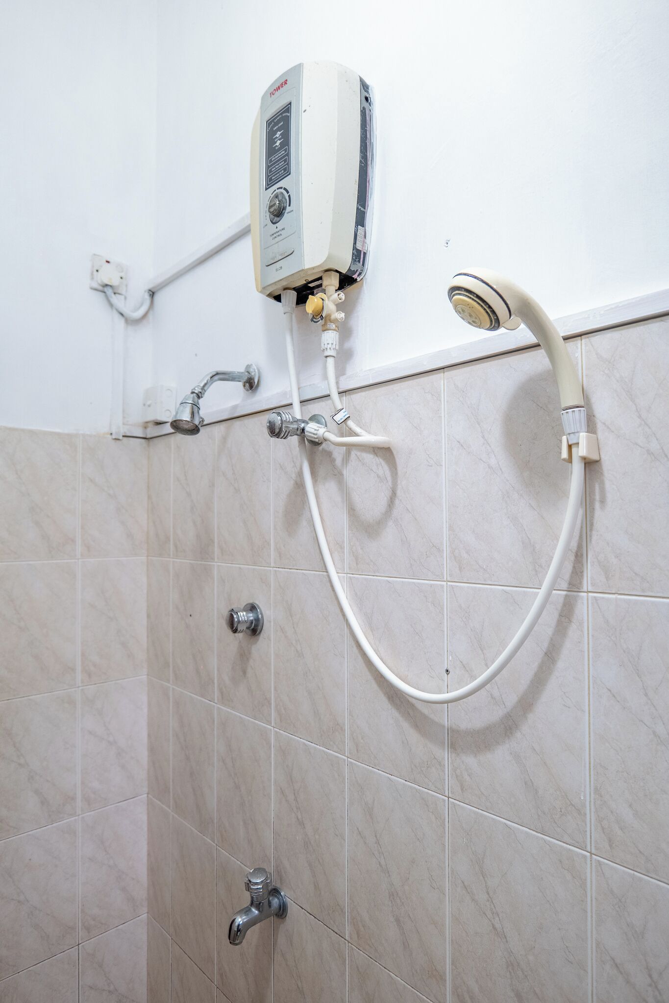 A shower with a control panel, a handheld showerhead, and two wall-mounted faucets.