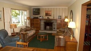 Una sala de estar acogedora con chimenea, televisor y comedor.