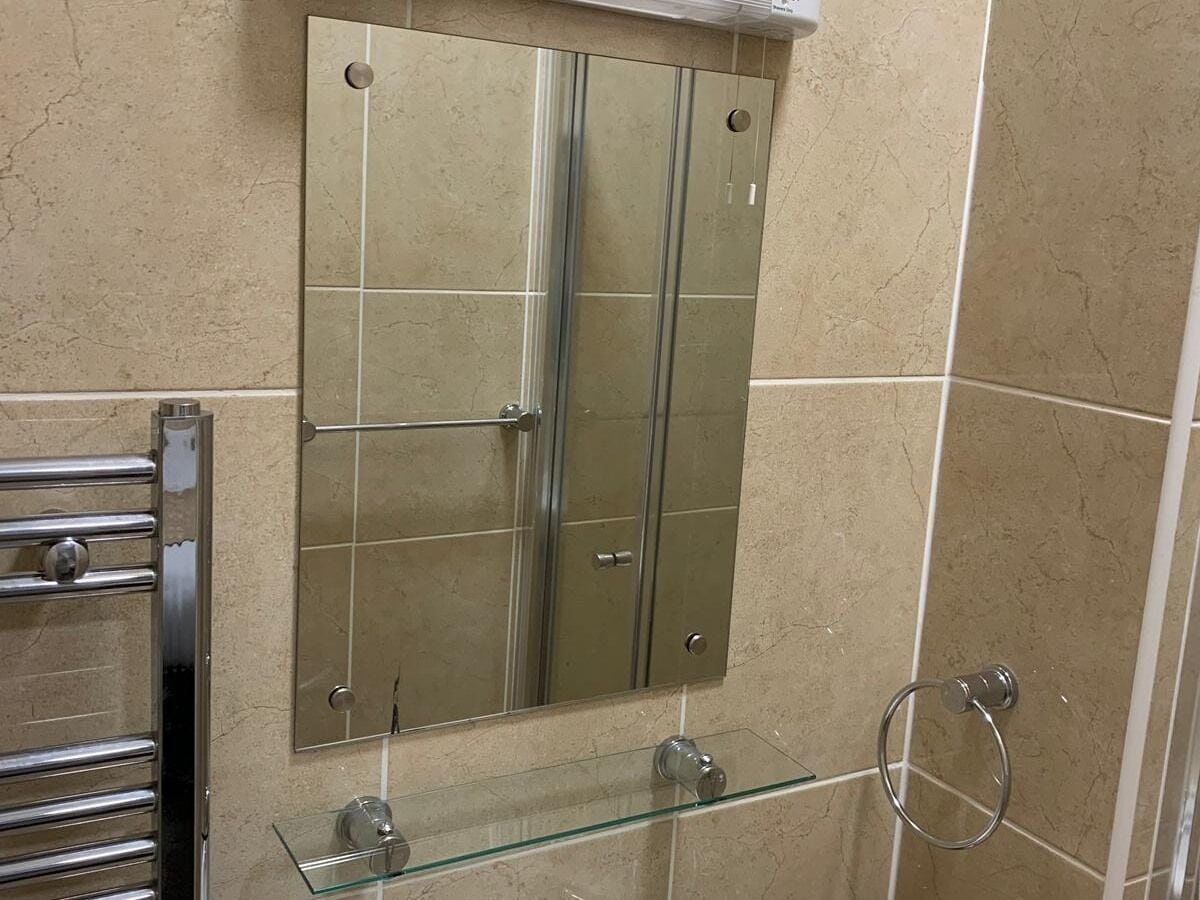 A bathroom with a glass shower enclosure, a glass sink, and a towel rack.
