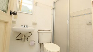 Un baño pequeño con inodoro, lavamanos y un espejo encima.