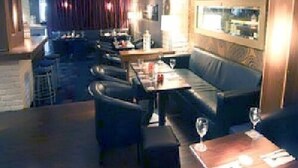 A restaurant with a long counter, booths, and a bar area. - Harty Costello Townhouse (Ballybunion)