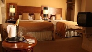 A hotel room with two beds, a television, a small table with a tray, and a lamp. - Harty Costello Townhouse (Ballybunion)