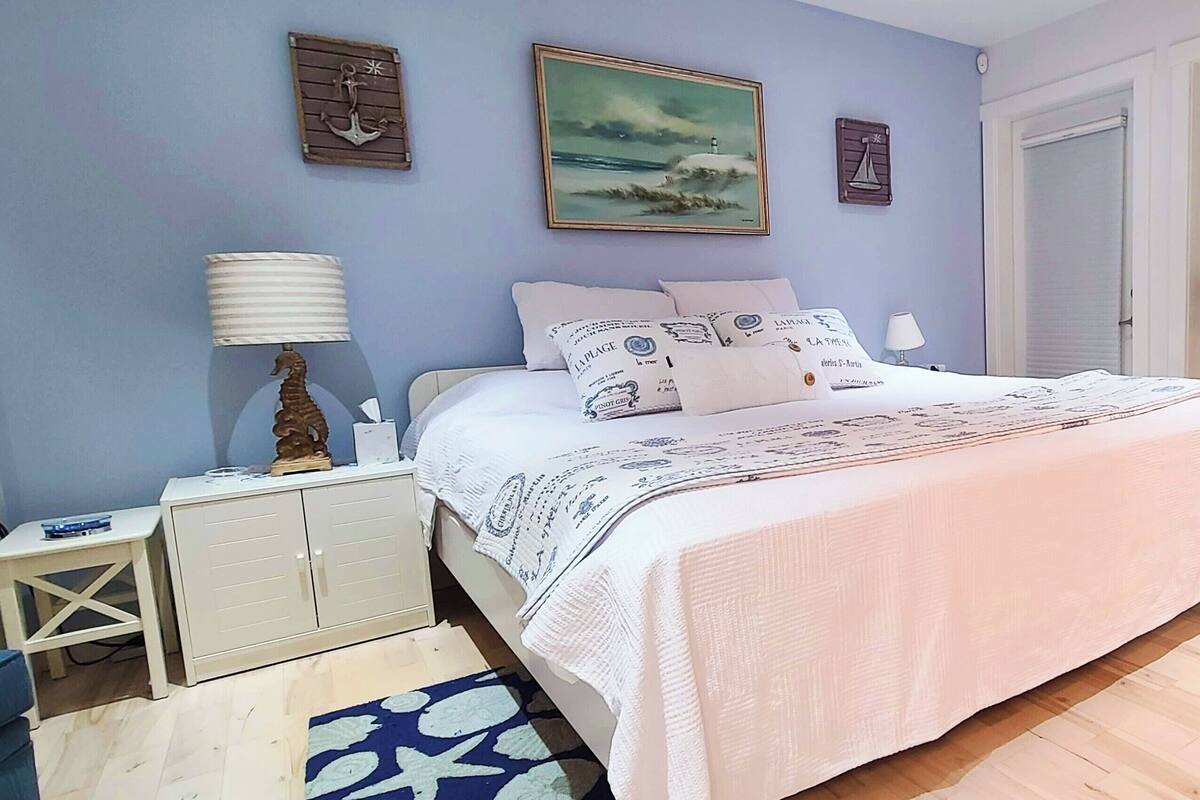 A neatly arranged bedroom with a bed, bedside tables, a desk, and a chair.