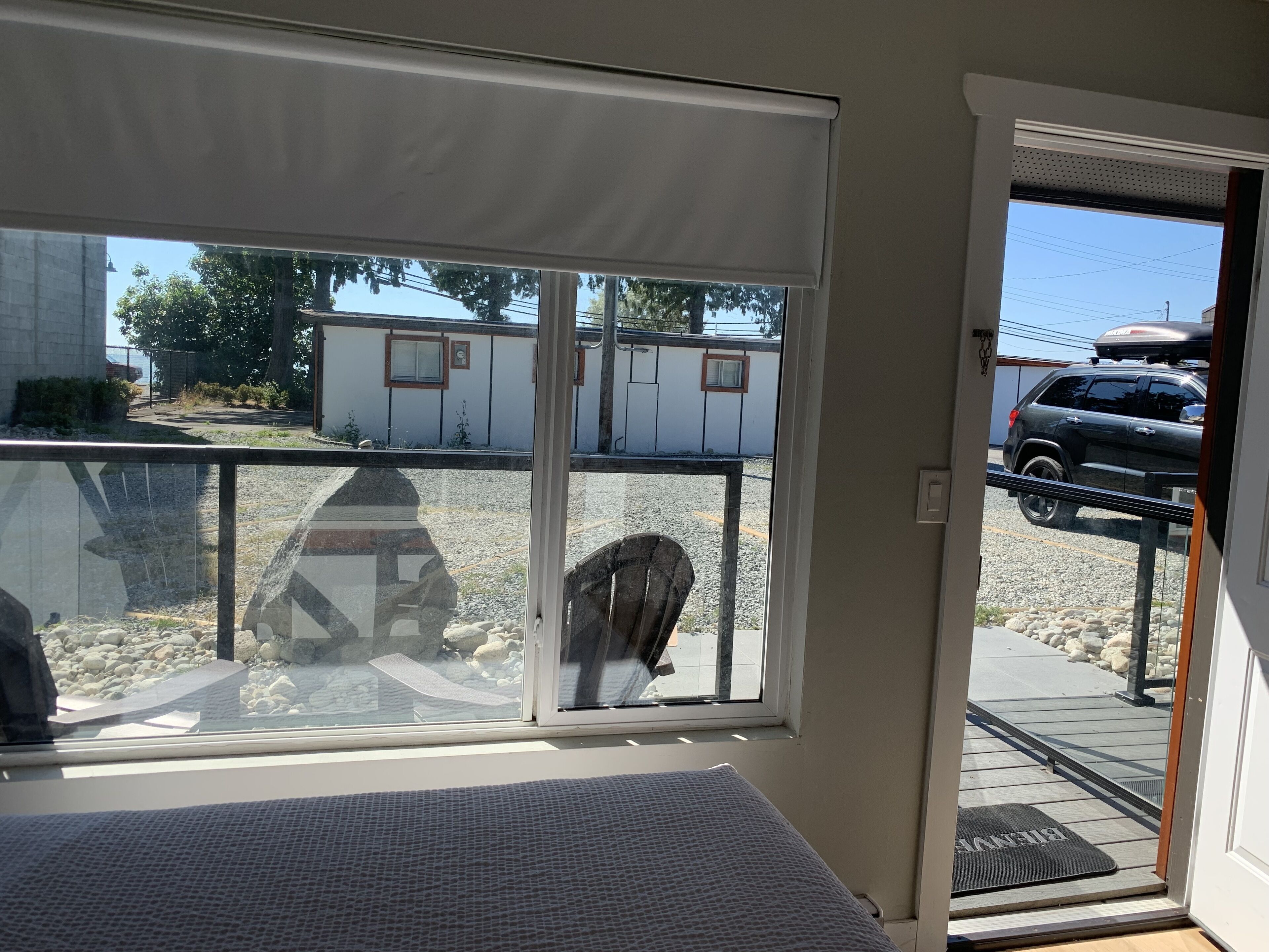 A room with a large window overlooking a parking area and a building.