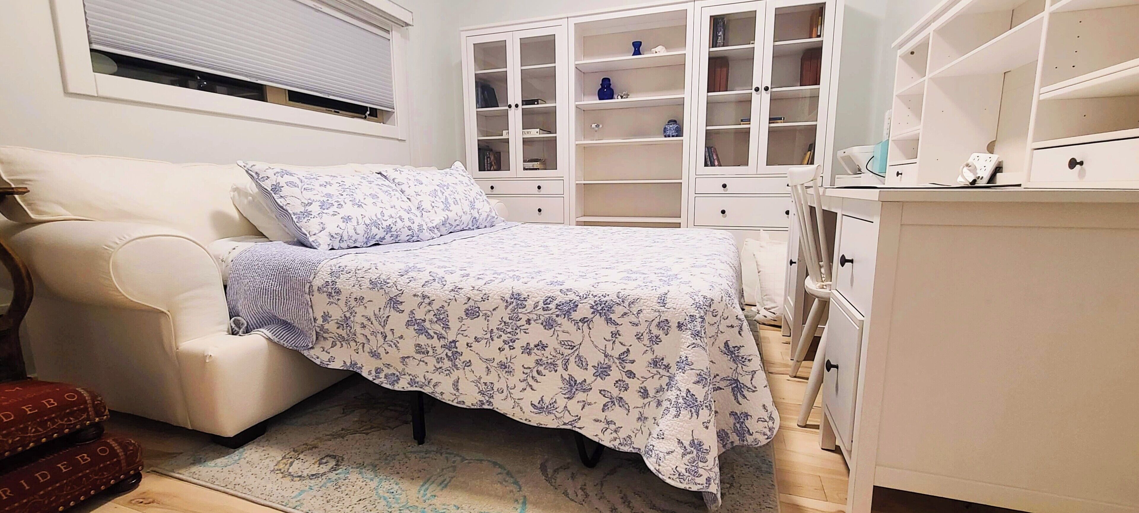 Un dormitorio con cama, un armario blanco y una ventana con persianas.