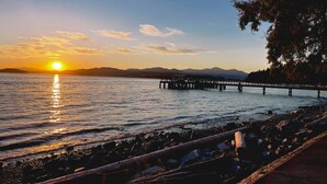 A sunset over a calm lake with a pier extending into the water.