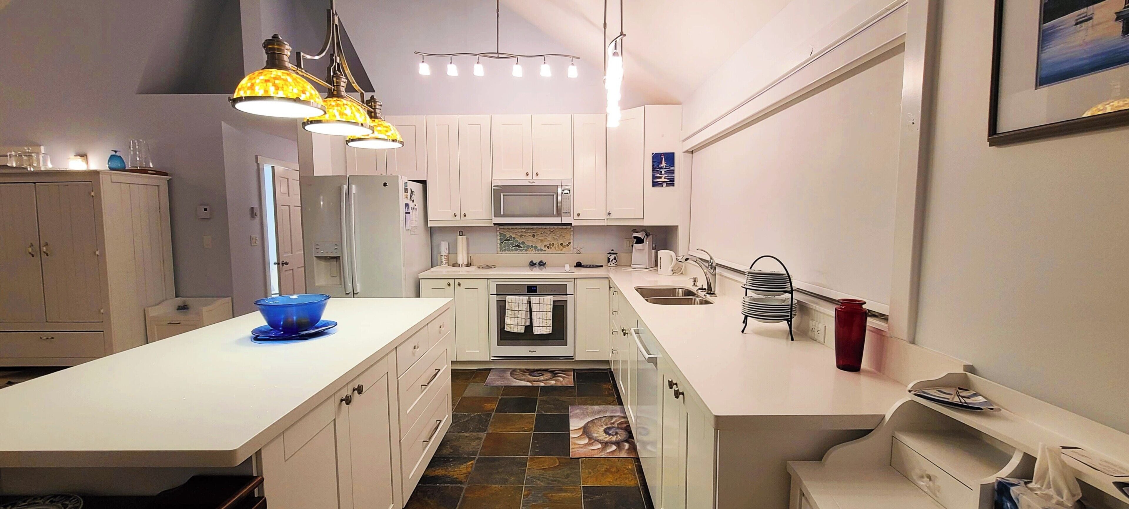 A compact kitchen with white cabinets, a central island, a microwave, and a stove.