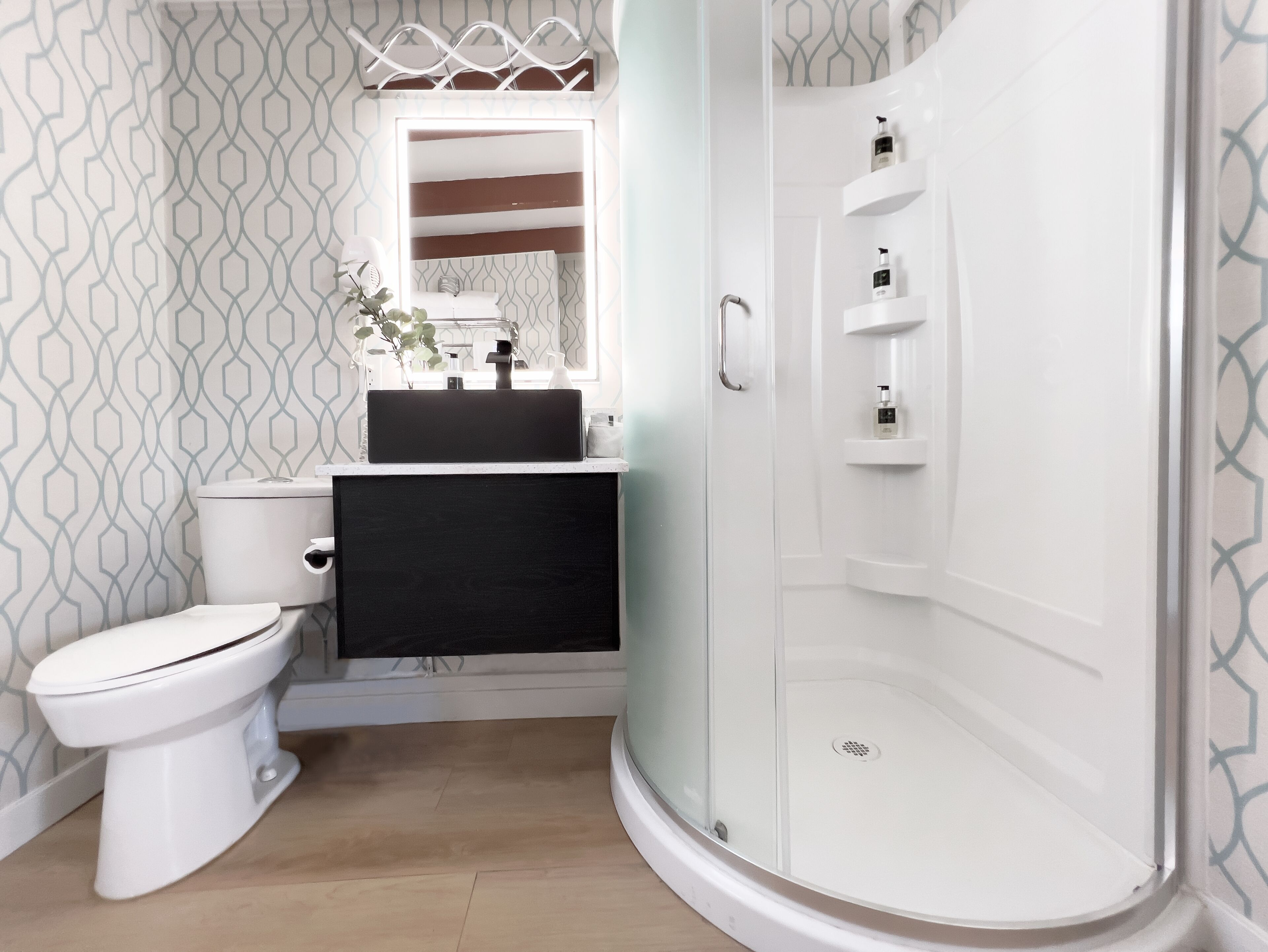 A modern bathroom with a toilet, sink, and shower.