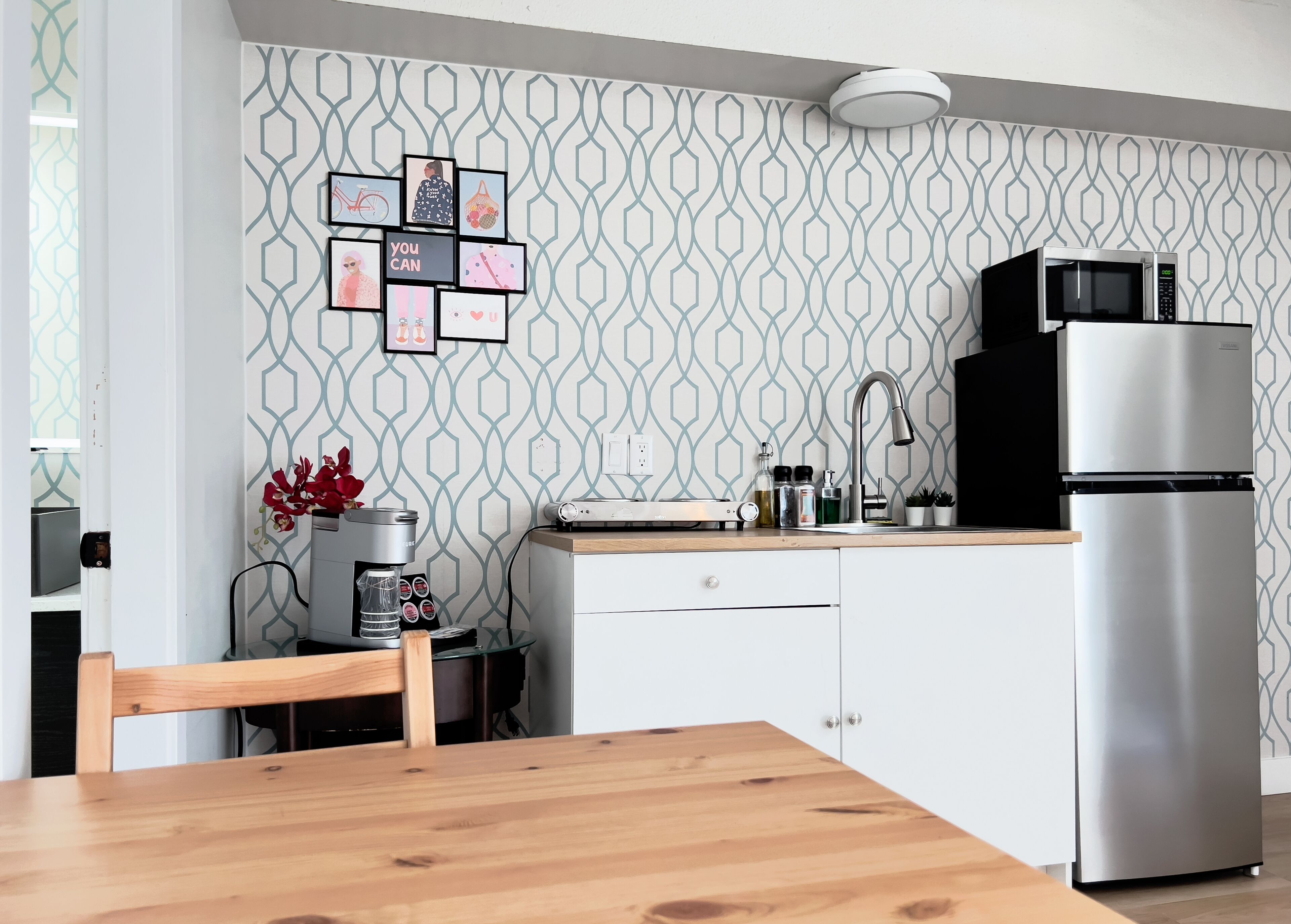 A modern kitchen with a patterned backsplash, a stainless steel refrigerator, and a coffee machine.