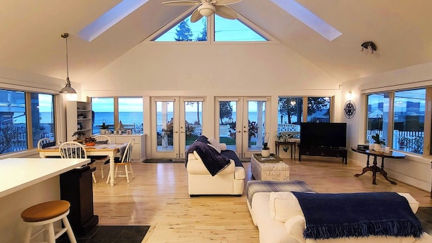A spacious living area with a high ceiling, large windows, and a view of the sea.