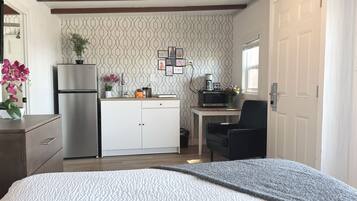 Una habitación pequeña con cama, kitchenette y un rincón de descanso.