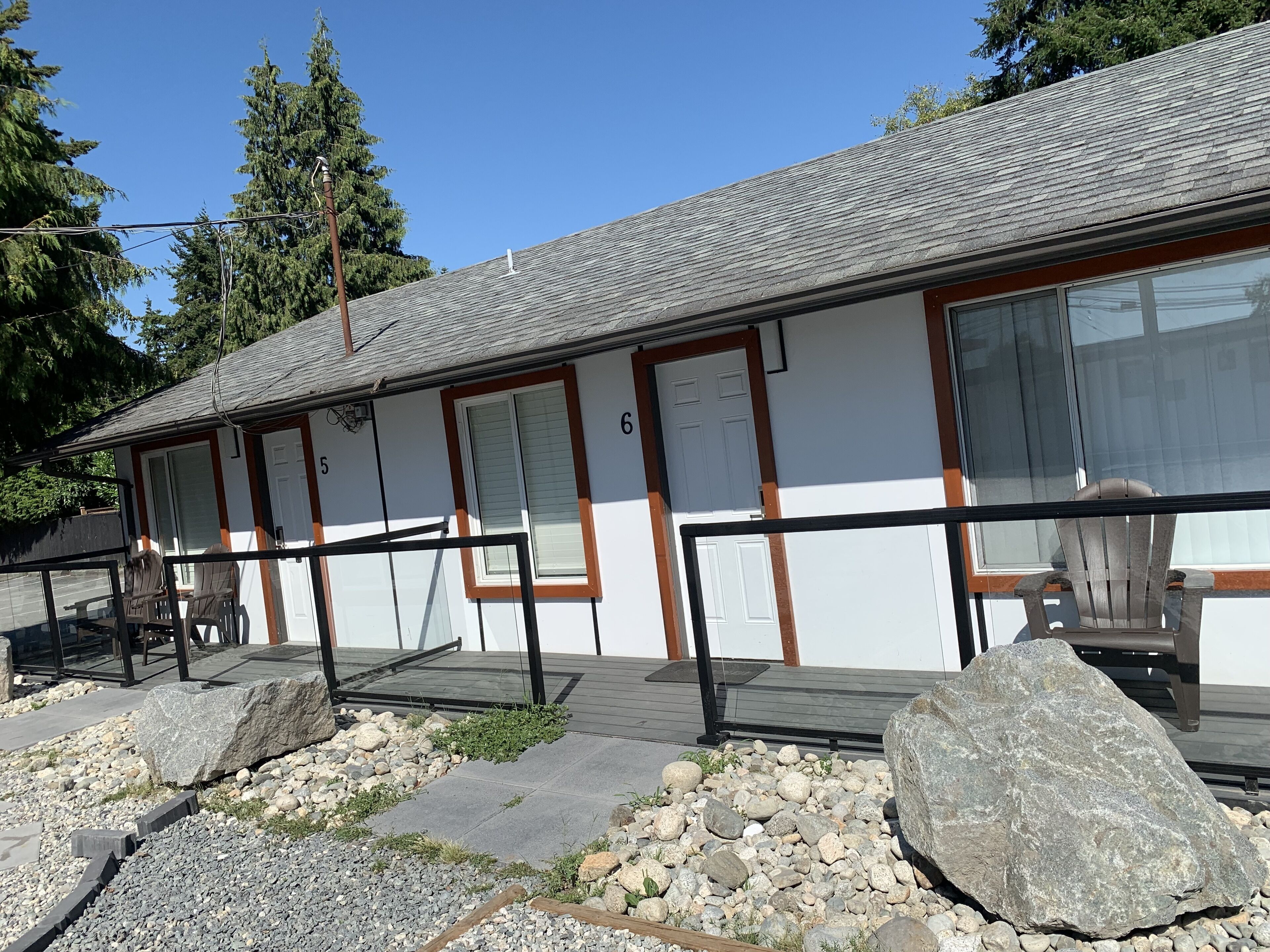 A building with numbered rooms, a wooden deck, and a stone pathway.