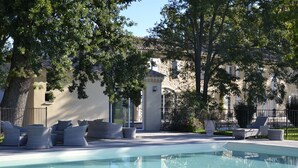 Une piscine avec des chaises longues et, en arrière-plan, un bâtiment en pierre.