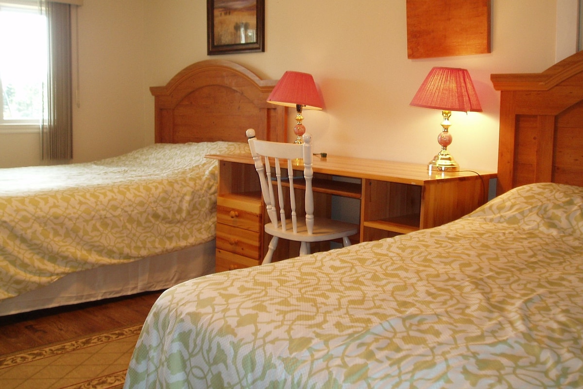 Una habitación de hotel con dos camas, un escritorio de madera, una silla y dos lámparas.