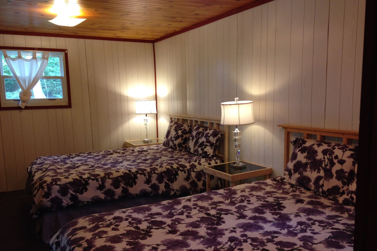 Una habitación con dos camas, cada una con ropa de cama de estampado floral, cabeceros de madera y lámparas de noche.