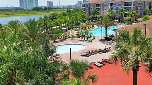 A resort with a pool, palm trees, and a view of the city skyline. - Universal Studio's Area Apt by CozyKey (Orlando)
