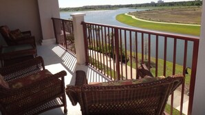 A balcony with wicker furniture overlooking a river. - Universal Studio's Area Apt by CozyKey (Orlando)