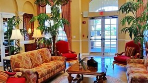 A lobby with a sofa, armchairs, a coffee table, and potted plants. - Universal Studio's Area Apt by CozyKey (Orlando)
