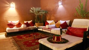 A cozy lounge area with a sofa set, a dining table with a cake, and a potted plant. - Dar Pamella (Marrakech)
