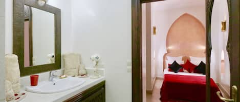 A bathroom with a sink, mirror, and toiletries.