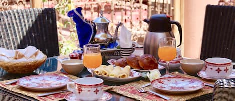 A breakfast table set with plates, bowls, a coffee pot, and a glass of orange juice.