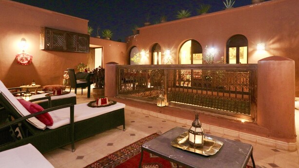 A well-lit outdoor lounge area with a sofa, a table with a tray, and a decorative lantern. - Dar Pamella (Marrakech)