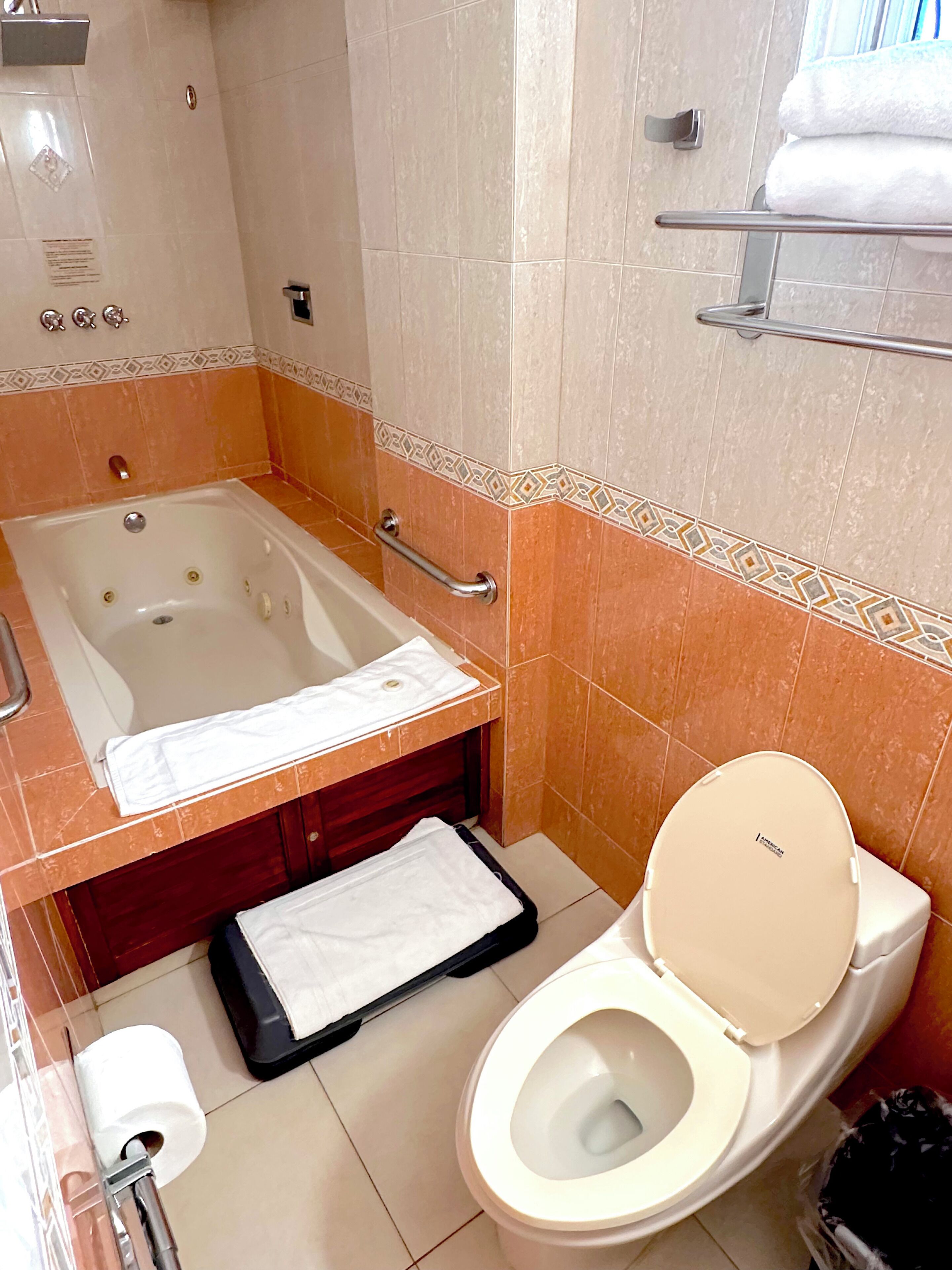 Een badkamer met een bad, toilet en een handdoekhouder.