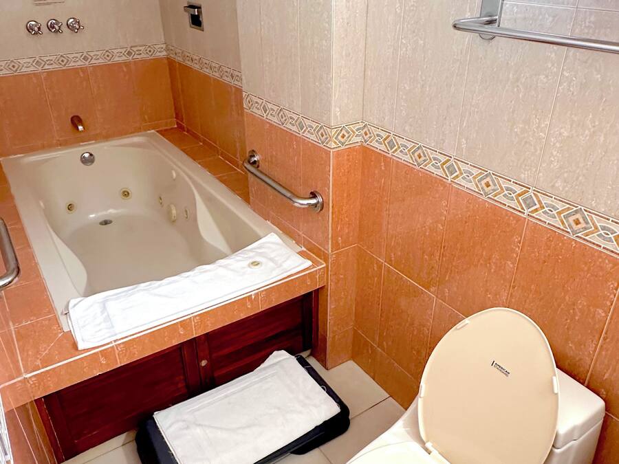 Een badkamer met een bad, toilet en een handdoekhouder.