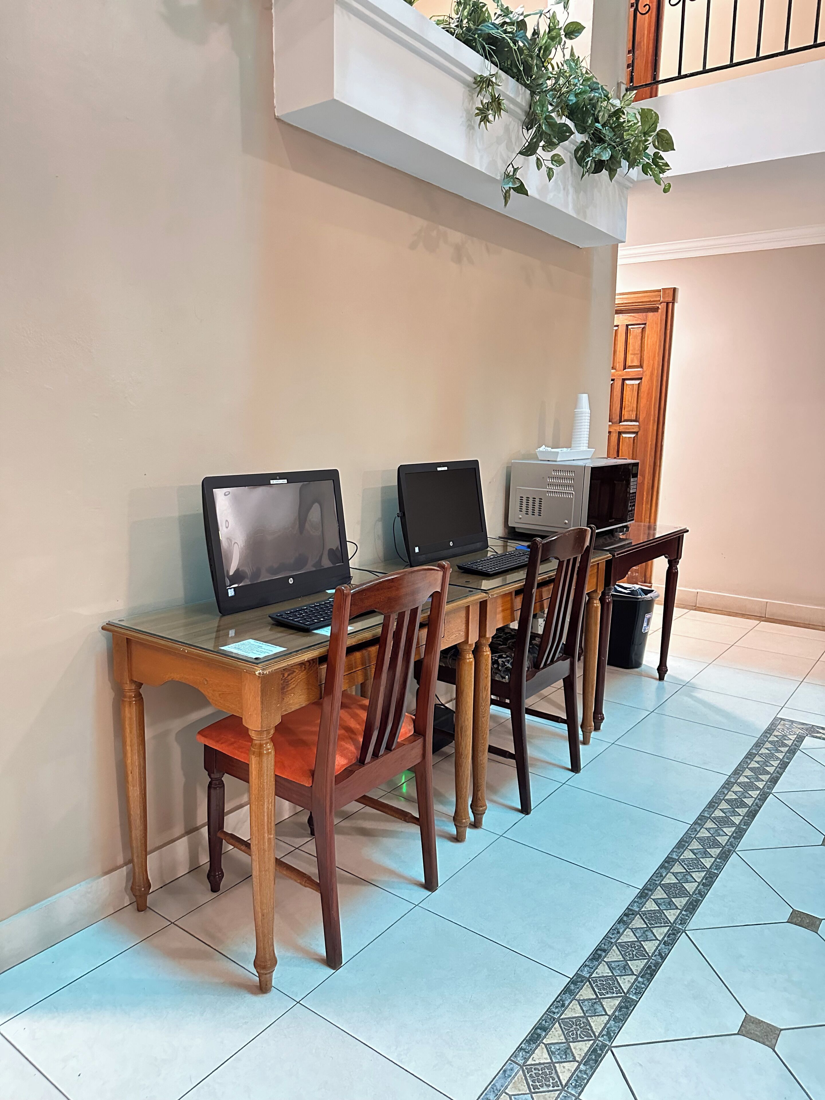A workspace with two laptops on a wooden table, a chair, and a trash bin.