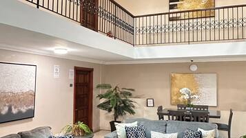 A multi-level living area with two grey sofas, a coffee table, and a dining table.