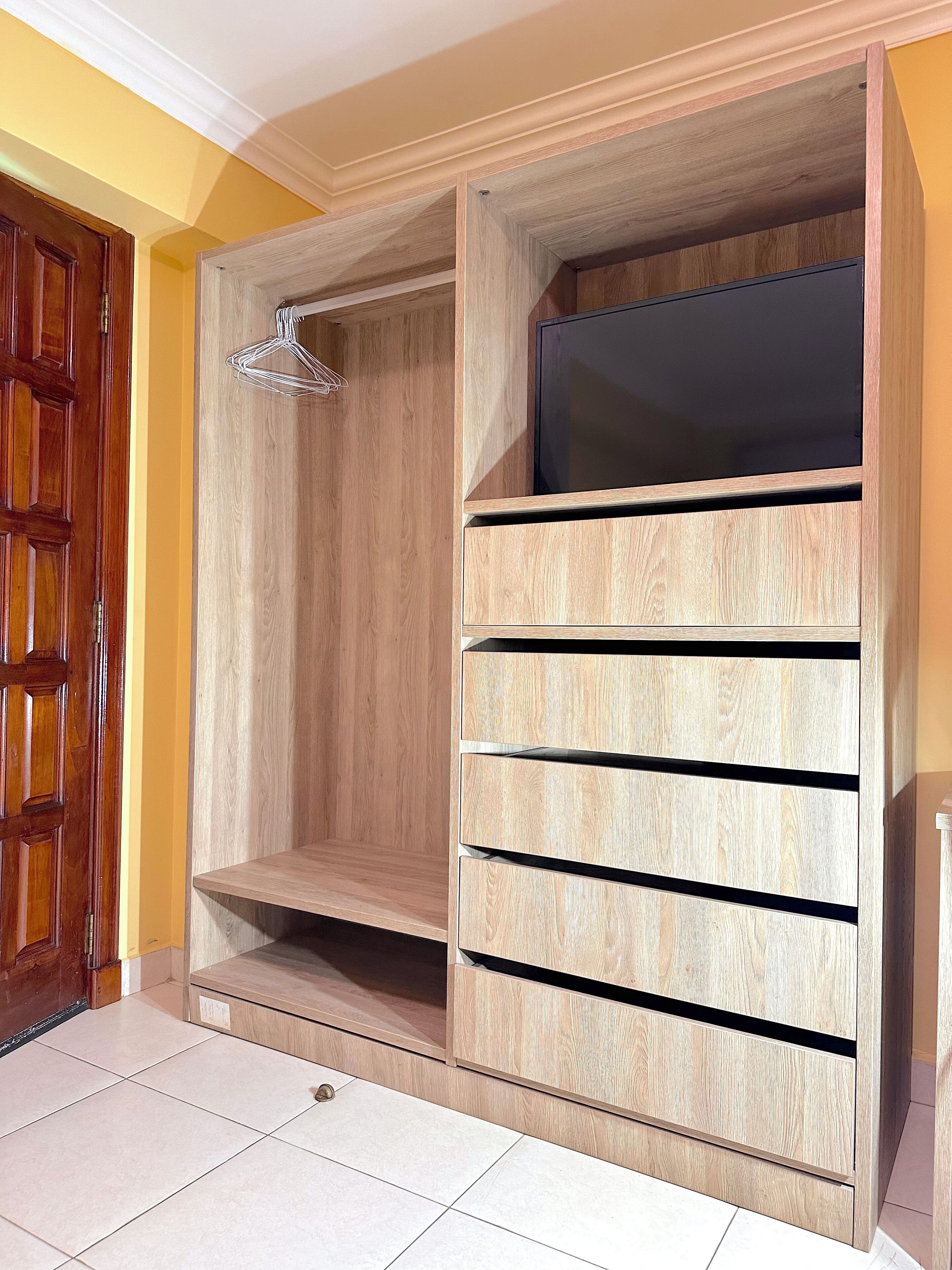 Un armario de madera con varios cajones y espacio para colgar.