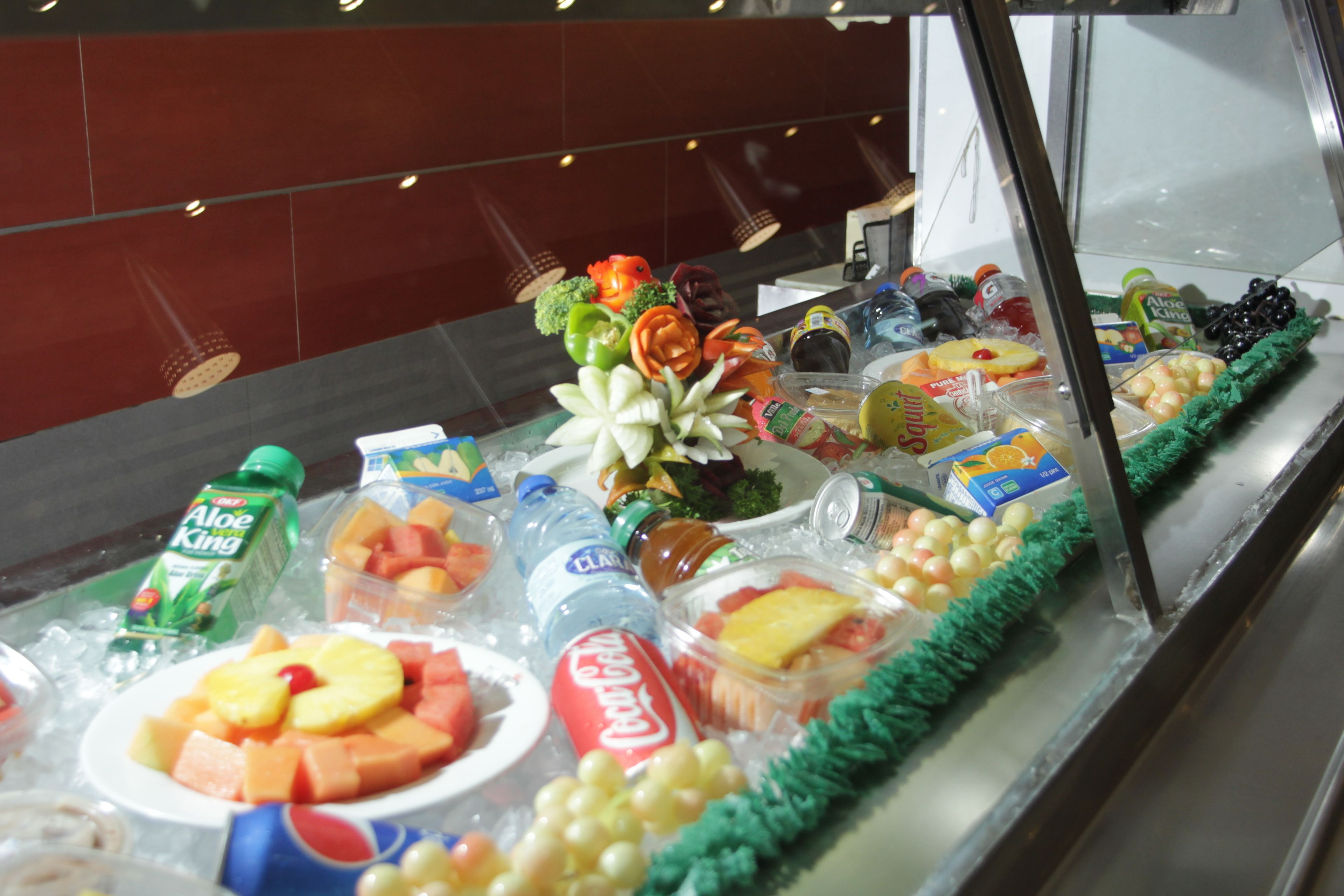 Una vitrina con frutas, verduras y bebidas diversas.