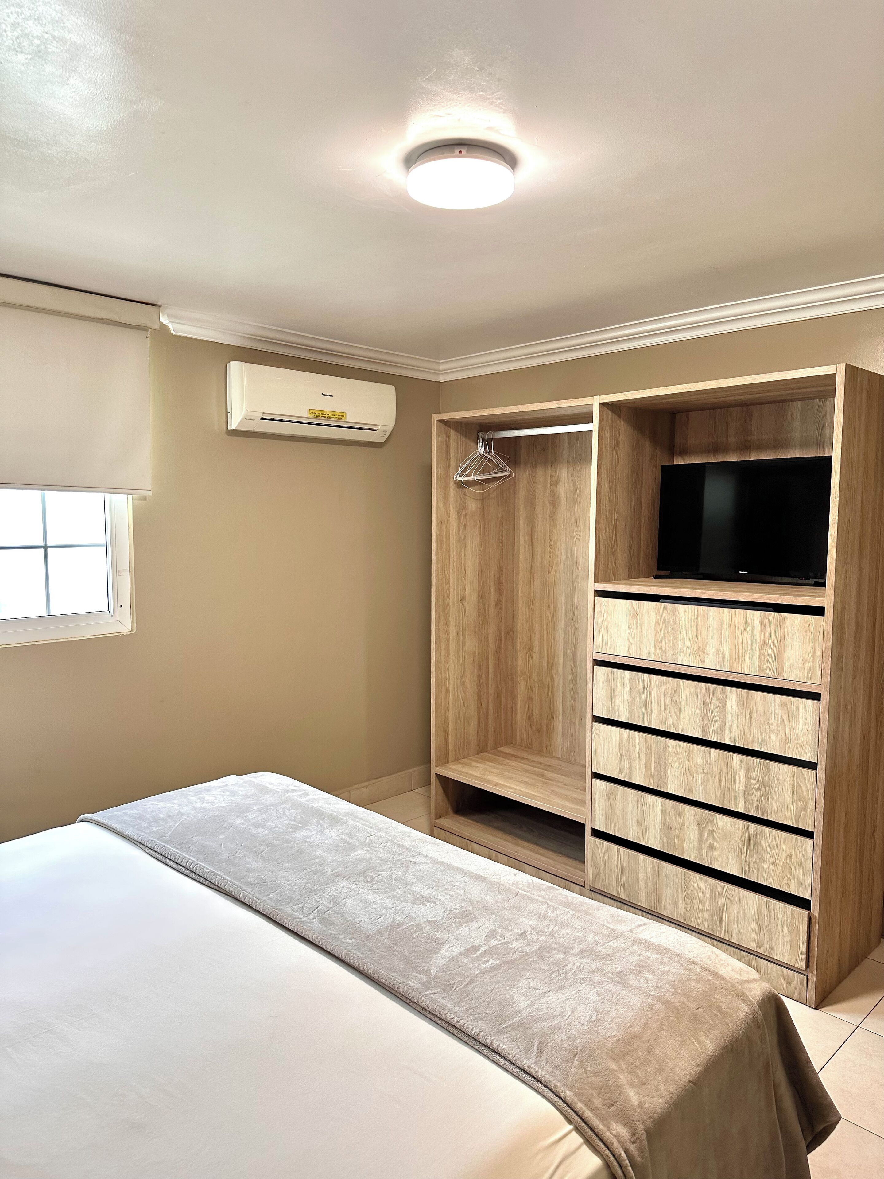 Ein Schlafzimmer mit einem Bett, einem Holzschrank und einer Klimaanlage.