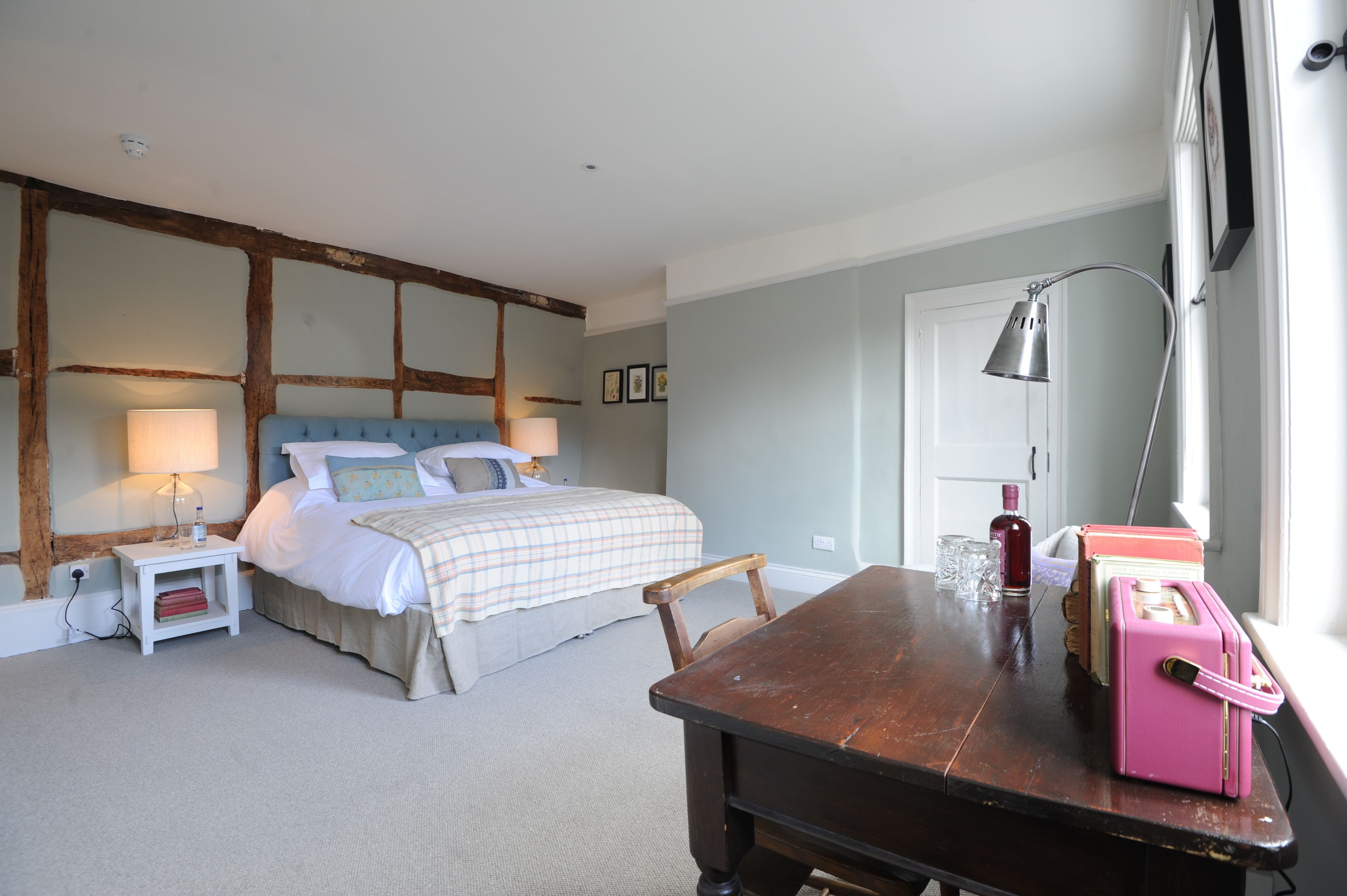 A bedroom with a bed, bedside tables, a wooden table, and a window.