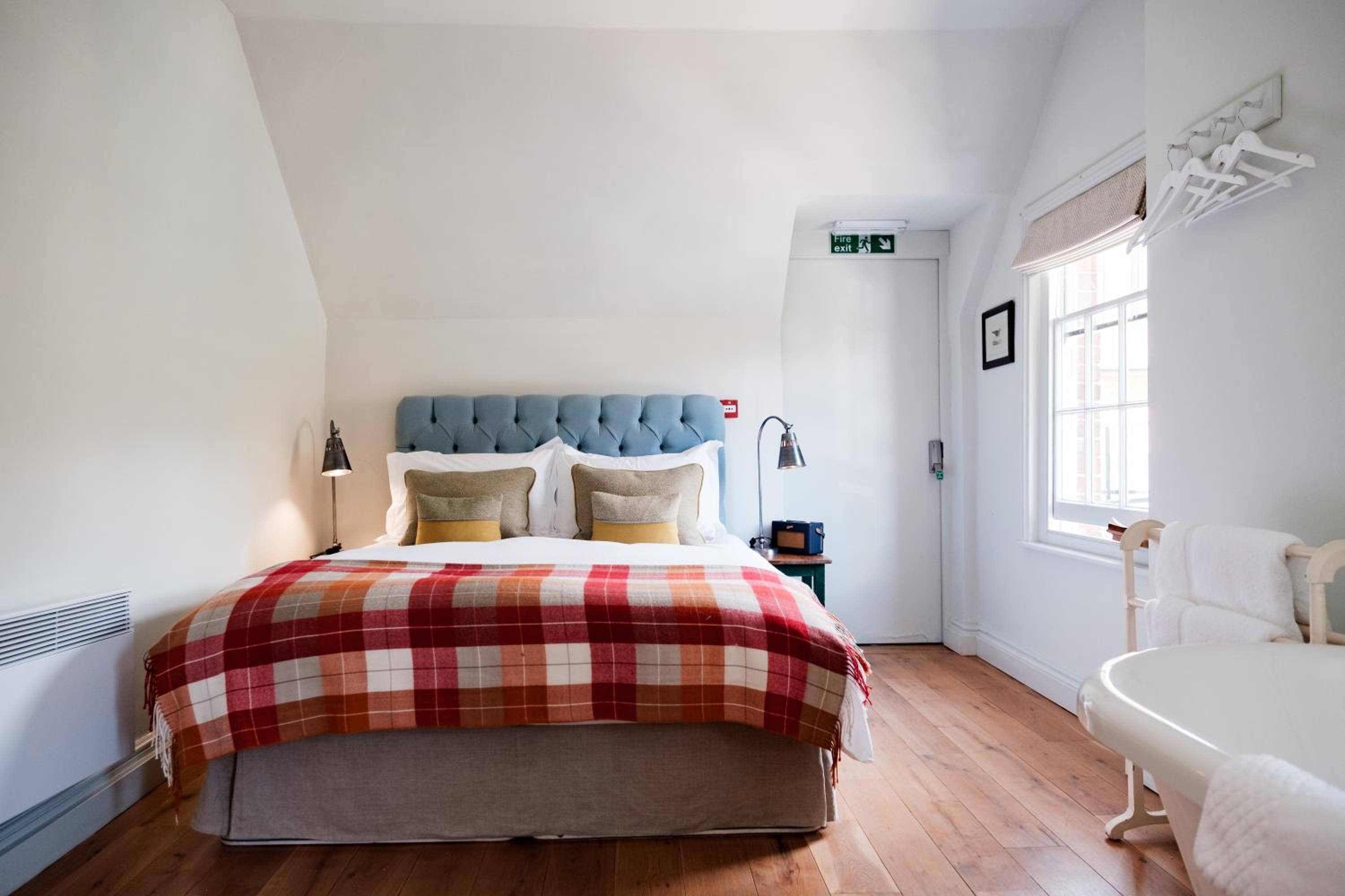 A bedroom with a bed, a nightstand, a window, and a white chair.