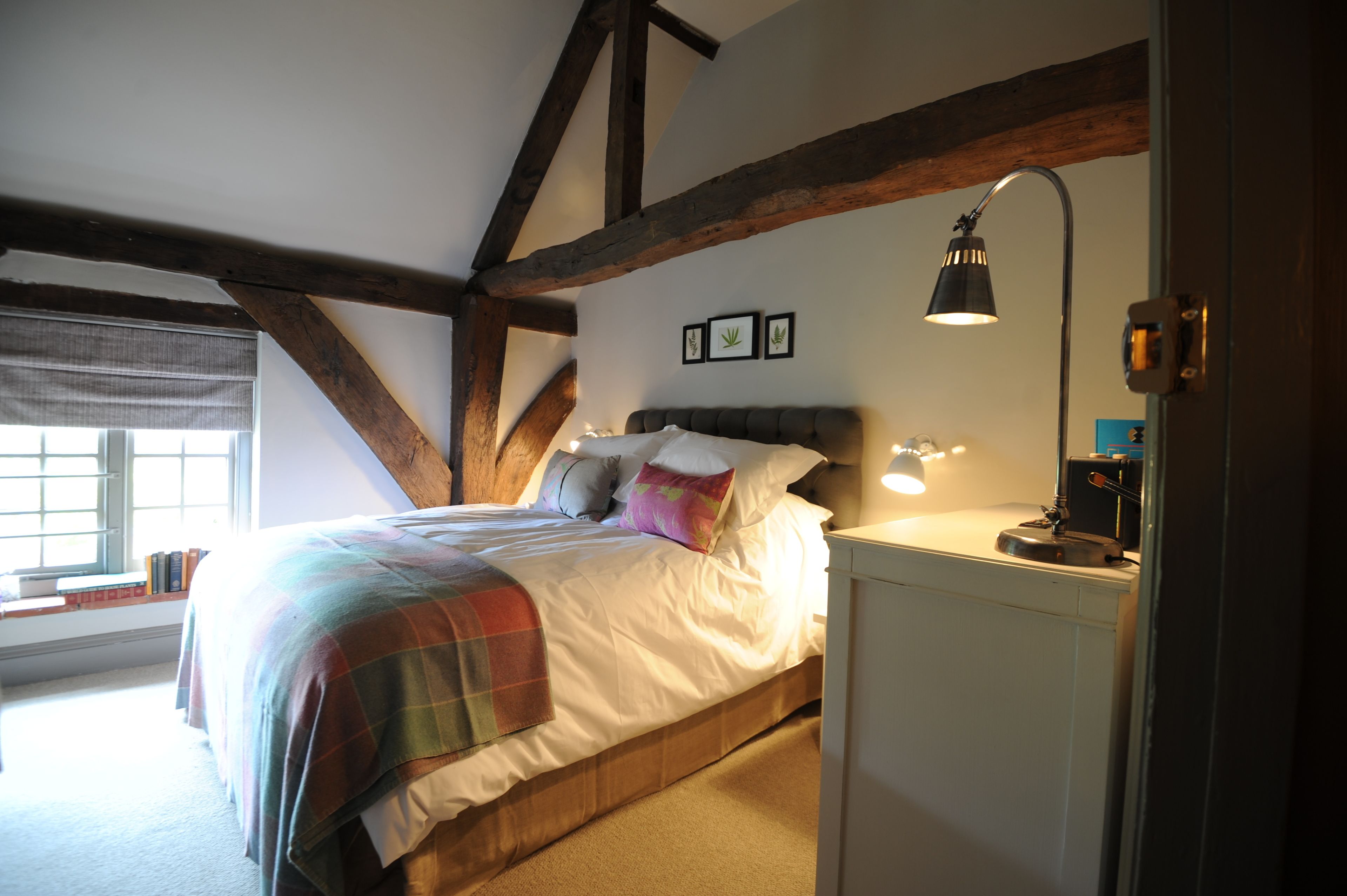 A bedroom with a bed, a nightstand, a lamp, and a window with blinds.