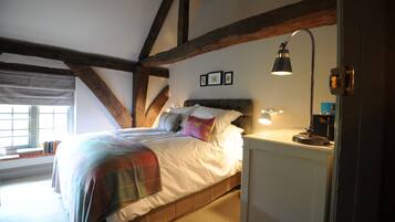 A bedroom with a bed, a nightstand, a lamp, and a window with blinds.