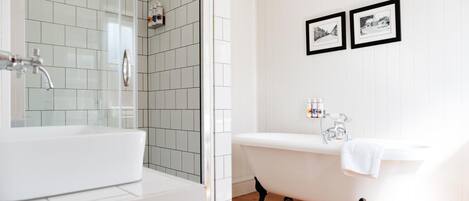 A bathroom with a white sink, a freestanding bathtub, and two framed pictures on the wall.