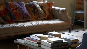 A cozy living room with a tufted sofa, colorful pillows, and a coffee table with books.