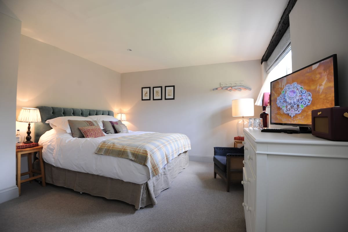 A bedroom with a bed, bedside lamps, a dresser, and a television.