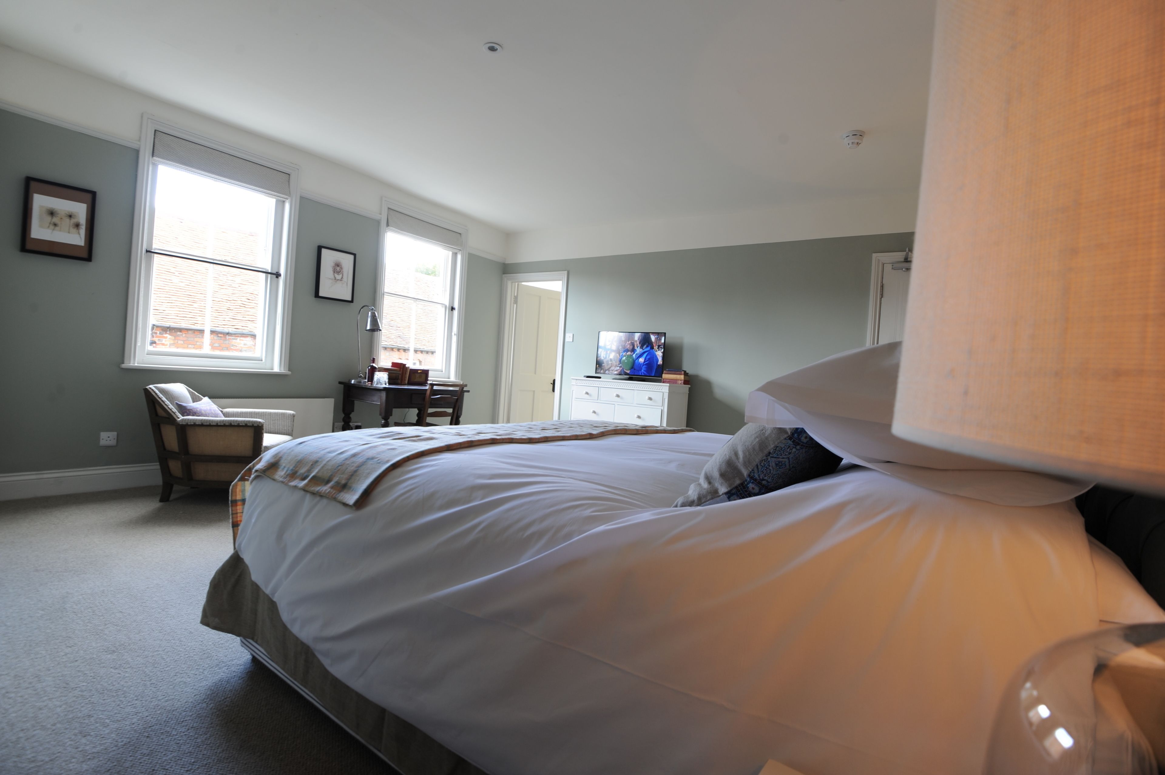 A bedroom with a large bed, a chair, a dresser, and a television.