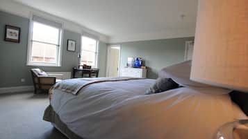 A bedroom with a large bed, a chair, a dresser, and a television.
